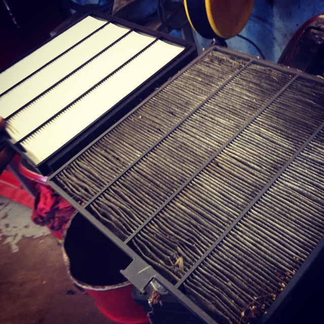 Clean cabin air filter next to a very dirty used filter.